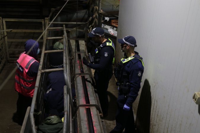 Police speak with activists chained inside race