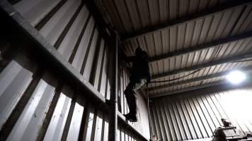 An investigator climbs a wall to look for places to install hidden cameras - Captured at Wal's Bulk Meats, Stowport TAS Australia.