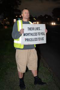 Cedar Meats Vigil - National Week Of Action 2025 - During the Shut Down Slaughterhouses Week of Action, we held a vigil outside of the Cedar Meats slaughterhouse in Brooklyn, Victoria.

During a two week investigation last year, our hidden cameras captured the handling and slaughter of animals, including newborn lambs and kids born in the holding pens of the slaughterhouse.

It was a Wednesday night when we gathered outside the slaughterhouse, holding signs and listening to music and speeches from investigators. We wanted to send a message to Cedar Meats, to let them know that we have not forgotten how they treat animals when they believe that no one is watching

We poured fake blood across their driveway as a visual reminder to everyone passing by, that animals arriving here are coming to their deaths. At the gates to the slaughterhouse, we each left a flower.

The images of animals whose deaths we have seen will haunt us forever, but we are determined to continue to fight in their name. - Captured at Cedar Meats, Brooklyn VIC Australia.