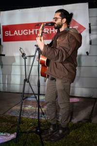 Cedar Meats Vigil - National Week Of Action 2025 - During the Shut Down Slaughterhouses Week of Action, we held a vigil outside of the Cedar Meats slaughterhouse in Brooklyn, Victoria.

During a two week investigation last year, our hidden cameras captured the handling and slaughter of animals, including newborn lambs and kids born in the holding pens of the slaughterhouse.

It was a Wednesday night when we gathered outside the slaughterhouse, holding signs and listening to music and speeches from investigators. We wanted to send a message to Cedar Meats, to let them know that we have not forgotten how they treat animals when they believe that no one is watching

We poured fake blood across their driveway as a visual reminder to everyone passing by, that animals arriving here are coming to their deaths. At the gates to the slaughterhouse, we each left a flower.

The images of animals whose deaths we have seen will haunt us forever, but we are determined to continue to fight in their name. - Captured at Cedar Meats, Brooklyn VIC Australia.