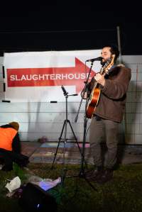 Cedar Meats Vigil - National Week Of Action 2025 - During the Shut Down Slaughterhouses Week of Action, we held a vigil outside of the Cedar Meats slaughterhouse in Brooklyn, Victoria.

During a two week investigation last year, our hidden cameras captured the handling and slaughter of animals, including newborn lambs and kids born in the holding pens of the slaughterhouse.

It was a Wednesday night when we gathered outside the slaughterhouse, holding signs and listening to music and speeches from investigators. We wanted to send a message to Cedar Meats, to let them know that we have not forgotten how they treat animals when they believe that no one is watching

We poured fake blood across their driveway as a visual reminder to everyone passing by, that animals arriving here are coming to their deaths. At the gates to the slaughterhouse, we each left a flower.

The images of animals whose deaths we have seen will haunt us forever, but we are determined to continue to fight in their name. - Captured at Cedar Meats, Brooklyn VIC Australia.
