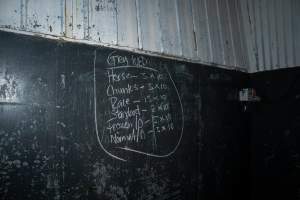 Blackboard inside processing room - Handheld photos taken at Goulburn Valley Stock Removers, owned by horse dealer Peter Loffel. Ex-racehorses are illegally killed on his residential property then transported to the knackery, where they are processed into pet food. The knackery also processes dead cows, mainly dairy cows. - Captured at Goulburn Valley Stock Removers, Shepparton North VIC Australia.