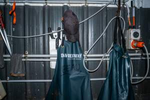Aprons and knives on wall - Handheld photos taken at Goulburn Valley Stock Removers, owned by horse dealer Peter Loffel. Ex-racehorses are illegally killed on his residential property then transported to the knackery, where they are processed into pet food. The knackery also processes dead cows, mainly dairy cows. - Captured at Goulburn Valley Stock Removers, Shepparton North VIC Australia.